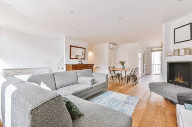 Günümüz minimalist tasarımı. Hafif stüdyo dairesinin ahşap masası ve oturma odası ile beyaz duvarları ve parke zemini arasında yemek masası ve sandalyeleri var.