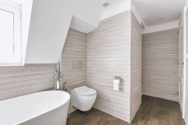 Çağdaş dairenin küçük fayanslı banyosunda lavabo ve duş arasında bulunan sifon tuvaleti