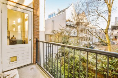 Dar tuğlalı balkon, metal parmaklıklar ve kapı.