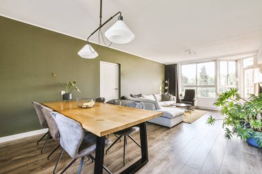 Günümüz minimalist tasarımı. Hafif stüdyo dairesinin ahşap masası ve oturma odası ile beyaz duvarları ve parke zemini arasında yemek masası ve sandalyeleri var.