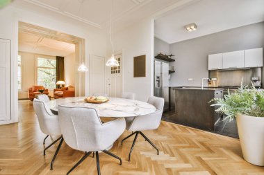 Günümüz minimalist tasarımı. Hafif stüdyo dairesinin ahşap masası ve oturma odası ile beyaz duvarları ve parke zemini arasında yemek masası ve sandalyeleri var.