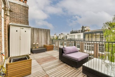 Parlak ahşap balkon, metal parmaklıklar, tahta sandalye ve kapı.