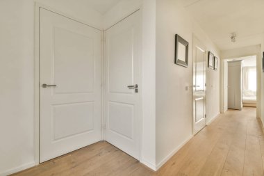 Beyaz duvarları ve aynalı gardırobu ve minimalist tarzda parke zemini olan boş dar koridor manzarası.