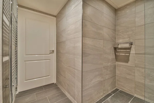 Interior of contemporary bathroom with shabby beige walls and partitions and white door at home