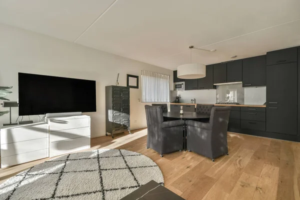 Square table placed on mat near couch and TV in stylish living room of contemporary apartment