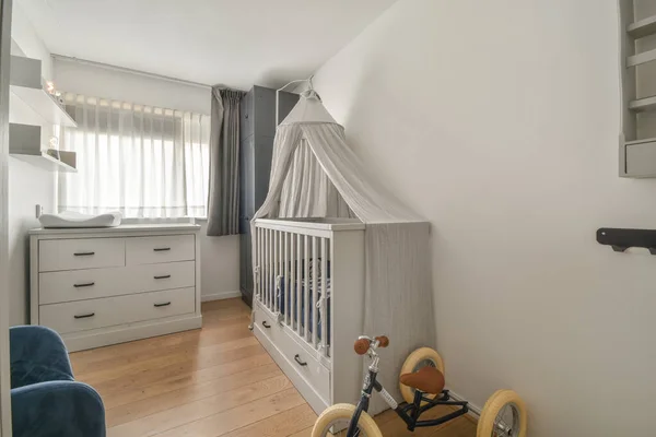 白屋室内 有婴儿床 靠窗有扶手椅 白天有蓝色抽屉 — 图库照片