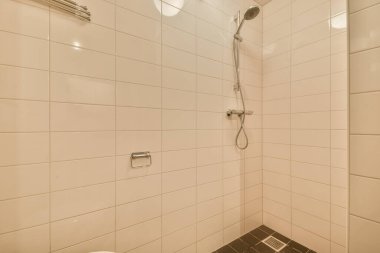 Duş muslukları cam bölmenin yanındaki fayanslı duvara bağlı ve evdeki tuvaletteki süs pervazı.