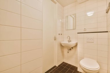 Modern sifon tuvaleti ve seramik lavabo aynanın yanındaki beyaz fayanslı duvarlara ve evdeki küçük tuvaletteki havluya monte edildi.