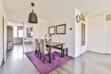 Günümüz minimalist tasarımı. Hafif stüdyo dairesinin ahşap masası ve oturma odası ile beyaz duvarları ve parke zemini arasında yemek masası ve sandalyeleri var.