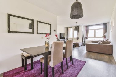 Günümüz minimalist tasarımı. Hafif stüdyo dairesinin ahşap masası ve oturma odası ile beyaz duvarları ve parke zemini arasında yemek masası ve sandalyeleri var.