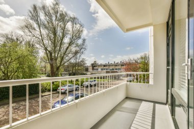 Dar tuğlalı balkon, metal parmaklıklar ve kapı.