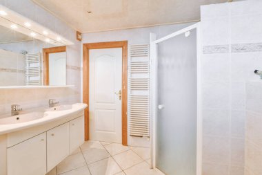 Aynalı lavabo ve temiz küvet modern banyoda cam kapılı ve beyaz fayanslı duvarları olan duş kutusunun yanında.