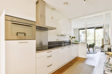 Minimalist tarzı beyaz mobilyalı, lavabolu ve sobalı bir ev mutfağı.