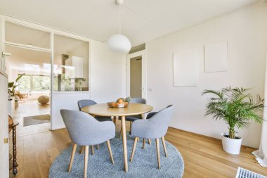 Masanın etrafına, modern dairede şık oturma odasının yemek alanında dekorasyonlar yerleştirilmiş kanepe ve koltuklar.