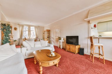 Modern apartmandaki dekorasyonlu ve televizyonlu, rahat koltuğun yanına yerleştirilmiş eski püskü ahşap masa.