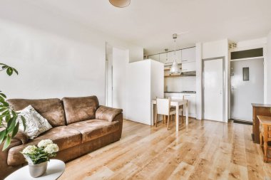 Günümüz minimalist tasarımı. Hafif stüdyo dairesinin ahşap masası ve oturma odası ile beyaz duvarları ve parke zemini arasında yemek masası ve sandalyeleri var.