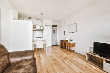 Günümüz minimalist tasarımı. Hafif stüdyo dairesinin ahşap masası ve oturma odası ile beyaz duvarları ve parke zemini arasında yemek masası ve sandalyeleri var.