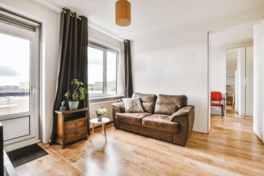 Günümüz minimalist tasarımı. Hafif stüdyo dairesinin ahşap masası ve oturma odası ile beyaz duvarları ve parke zemini arasında yemek masası ve sandalyeleri var.