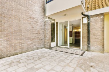 Levhalı, kaldırımlı ve ahşap kapılı bir binanın ön manzarası daireye çıkıyor.