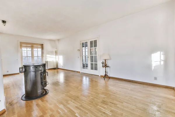 Modern counters with stools placed on wooden floor near fireplace in spacious room with white walls