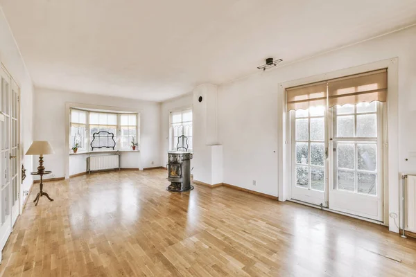 Modern counters with stools placed on wooden floor near fireplace in spacious room with white walls