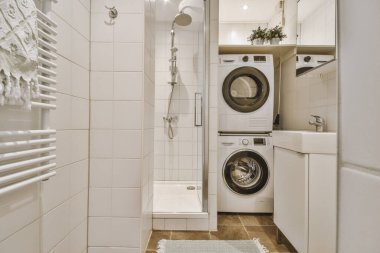 Çağdaş dairenin küçük fayanslı banyosunda lavabo ve duş arasında bulunan sifon tuvaleti