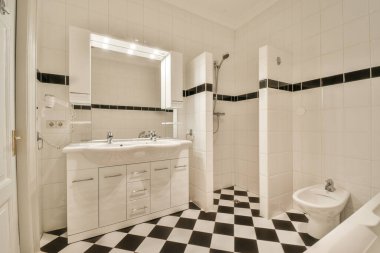 Sinks with mirrors and clean bathtub,toilet located near shower box with glass door in modern bathroom with white tiled walls