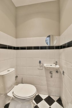 Lavabolu ve duvarlı, beyaz duvarlı ve kareli tuvaletli dar bir tuvalet.