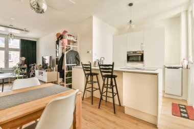 Modern apartmandaki dekorasyonlu ve televizyonlu, rahat koltuğun yanına yerleştirilmiş eski püskü ahşap masa.