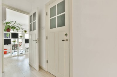 Çağdaş dairede ışık odasına açılan siyah duvar panelleri olan dar koridor.