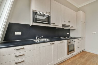 Pencereleri ve ahşap parke zemini olan boş beyaz mutfağın içi.