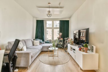 Modern apartmandaki dekorasyonlu ve televizyonlu, rahat koltuğun yanına yerleştirilmiş eski püskü ahşap masa.