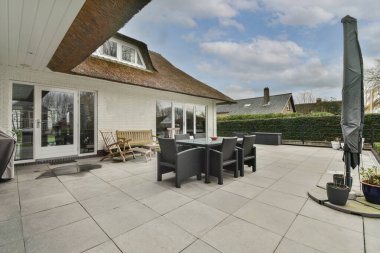 Oturma alanı ve ahşap çitlerin yanındaki küçük bahçesi olan düzgün asfaltlı bir avlu.