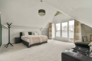 Modern minimalist tarzda pencereli mansard yatak odasındaki yeşil duvarın yanına konforlu yatak