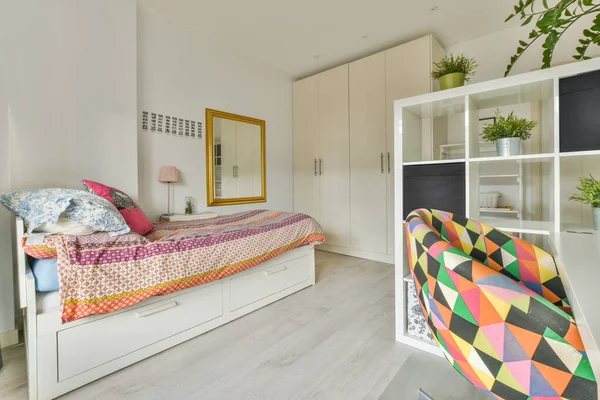 現代的なフラットのスタイリッシュなベッドルームでヴィンテージ画像とグレーの壁の近くに位置装飾のDuvetと枕と快適なベッドルーム — ストック写真