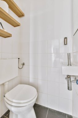 Lavabolu ve duvarlı, beyaz duvarlı ve kareli tuvaletli dar bir tuvalet.