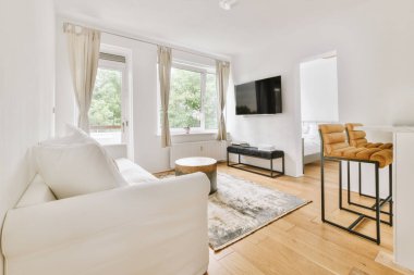 Günümüz minimalist tasarımı. Hafif stüdyo dairesinin ahşap masası ve oturma odası ile beyaz duvarları ve parke zemini arasında yemek masası ve sandalyeleri var.