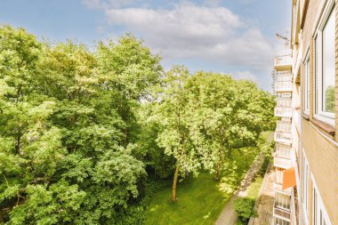 Eski tuğla binaların panoramik manzarası. Küçük balkondan park yerleri ve ağaçlar.