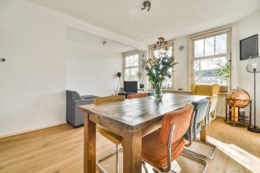 TV 'nin yanındaki koltuklar ve masa, çağdaş apartmandaki geniş odalı yemek alanına karşıdır.