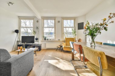 TV 'nin yanındaki koltuklar ve masa, çağdaş apartmandaki geniş odalı yemek alanına karşıdır.