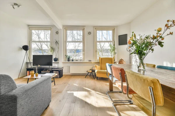 TV 'nin yanındaki koltuklar ve masa, çağdaş apartmandaki geniş odalı yemek alanına karşıdır.