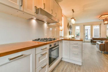 Minimalist tarzı beyaz mobilyalı, lavabolu ve sobalı bir ev mutfağı.