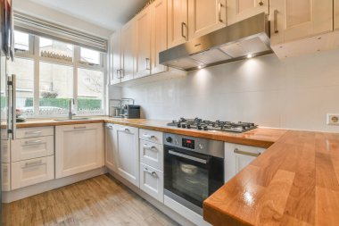 Minimalist tarzı beyaz mobilyalı, lavabolu ve sobalı bir ev mutfağı.