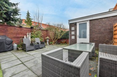 Oturma alanı ve ahşap çitlerin yanındaki küçük bahçesi olan düzgün asfaltlı bir avlu.