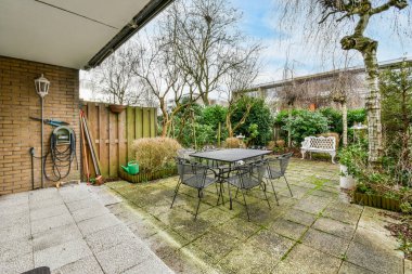 Oturma alanı ve ahşap çitlerin yanındaki küçük bahçesi olan düzgün asfaltlı bir avlu.