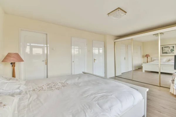 クイーンサイズベッドと大きな窓に対する古典的なアームチェア付きの光の寝室のインテリア — ストック写真