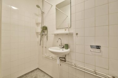 Lavabolu ve duvarlı, beyaz duvarlı ve kareli tuvaletli dar bir tuvalet.