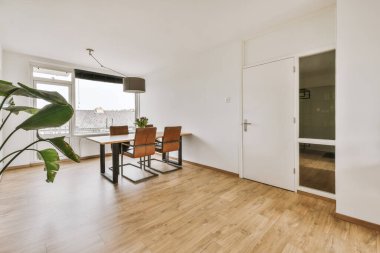 Modern apartmandaki dekorasyonlu ve televizyonlu, rahat koltuğun yanına yerleştirilmiş eski püskü ahşap masa.