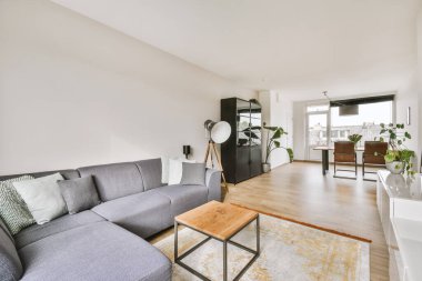 Modern apartmandaki dekorasyonlu ve televizyonlu, rahat koltuğun yanına yerleştirilmiş eski püskü ahşap masa.