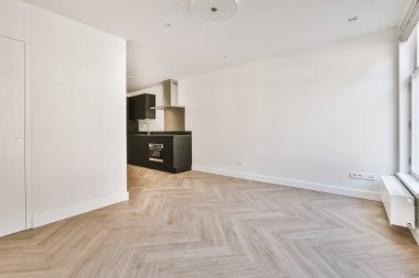 Pencereleri ve ahşap parke zemini olan boş beyaz mutfağın içi.